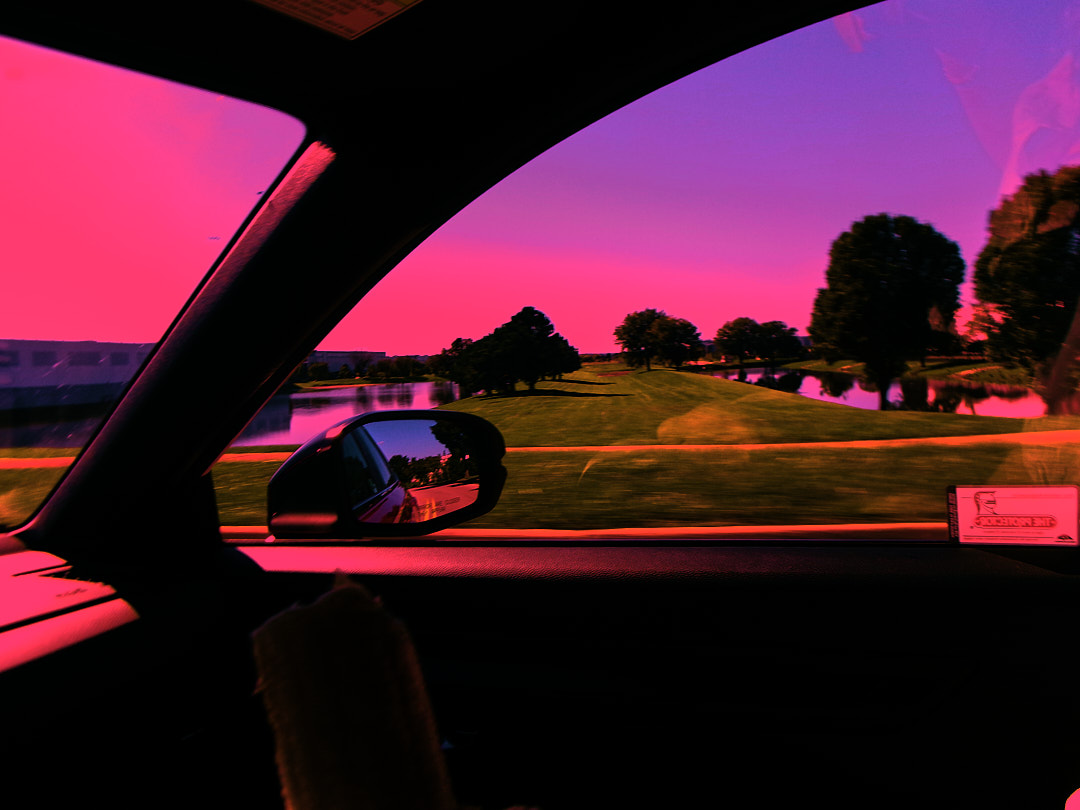 A side mirror and a pond seen from a car window