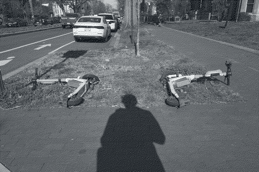 Two toppled scooters on a grass strip and the photographer's shadow